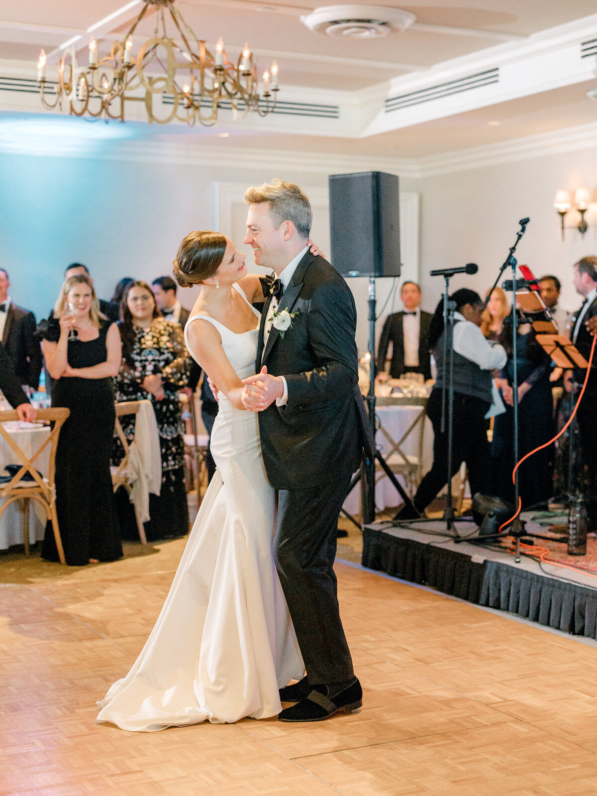 Bride and groom dancing in front of the band on stage while their wedding guests watch