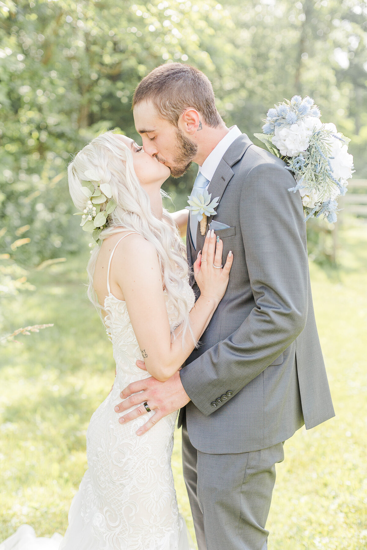Bride and groom share a kiss in for their formal wedding portraits. The bride's hand is resting on her groom's chest and the other hand has her bouquet draped around his neck. Captured by RI wedding photographer Lia Rose Weddings