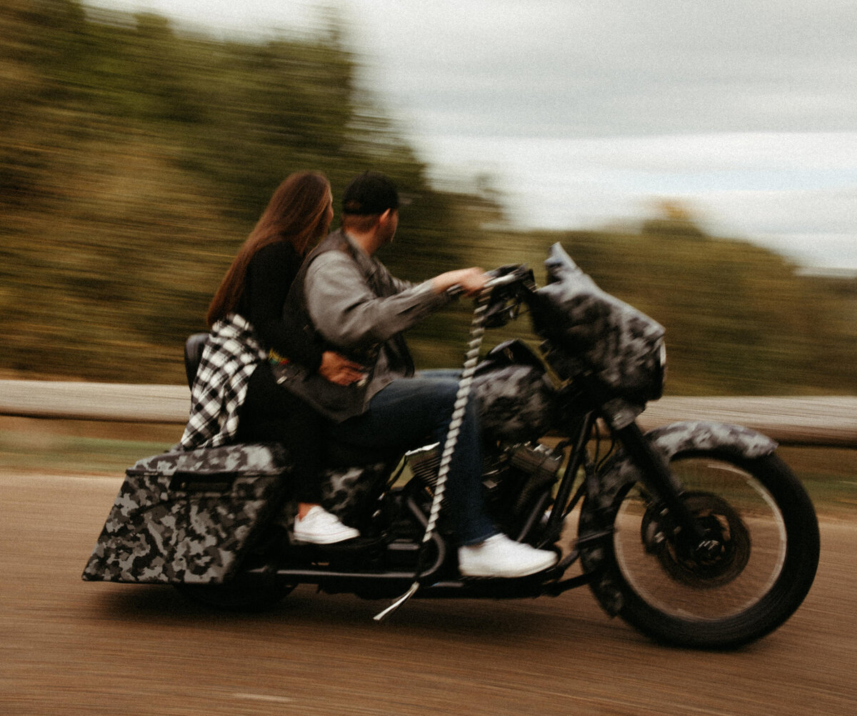 Couple riding motorcycle together down the road