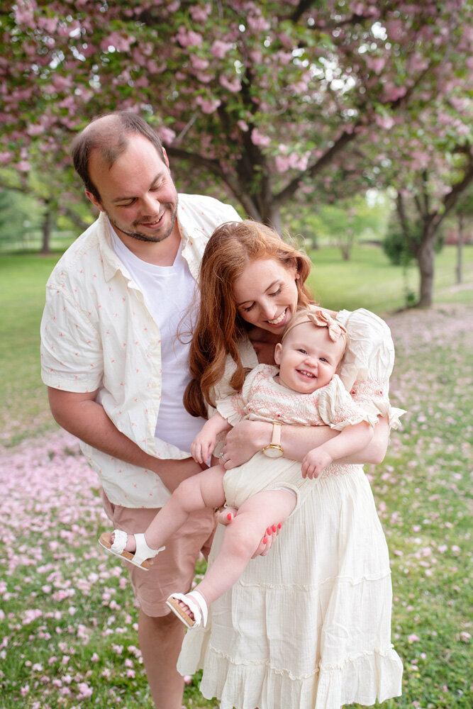 Family session of little girl with her parents surrounded by flowers