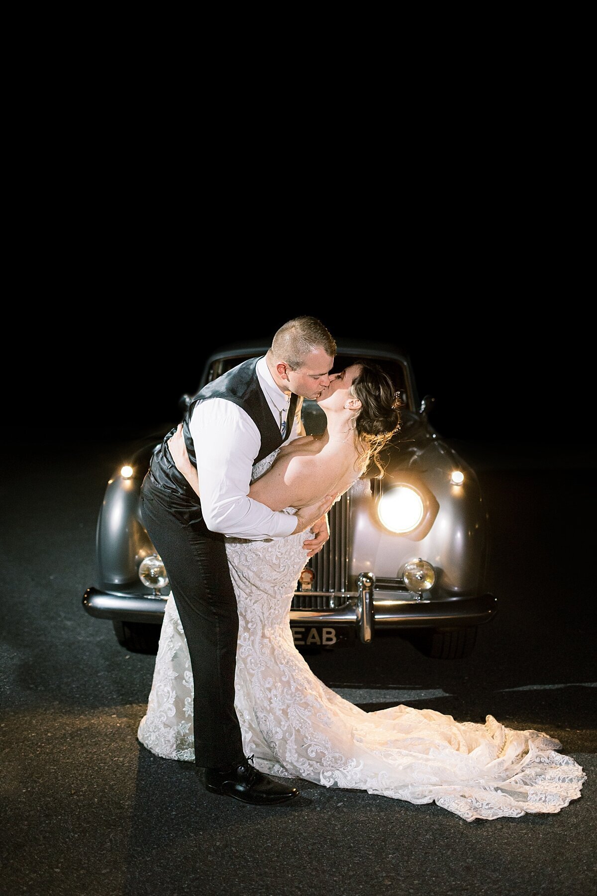 bride and groom kissing in front of vintage car
