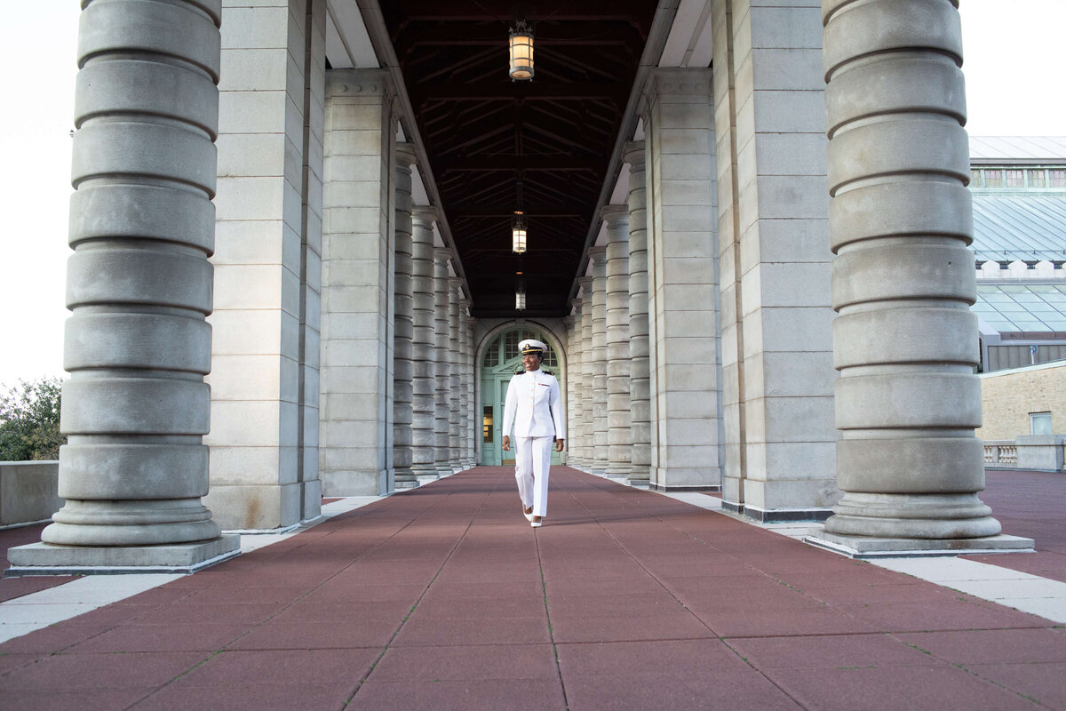 Naval Academy graduate walks in the hall on red beach at Naval Academy.