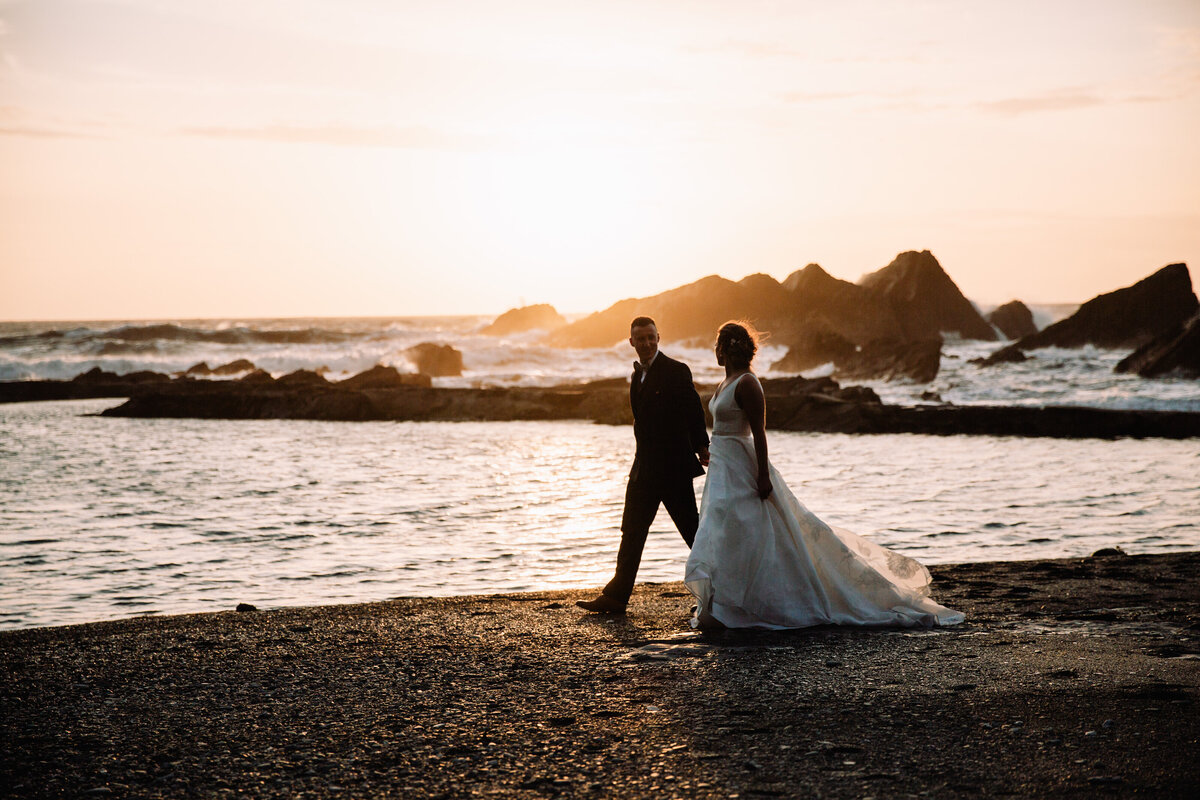 Newly married couple walking along the coast at Tunnels Beaches taken by  Cornwall Wedding Photographer and Devon Wedding Photographer Liberty Pearl