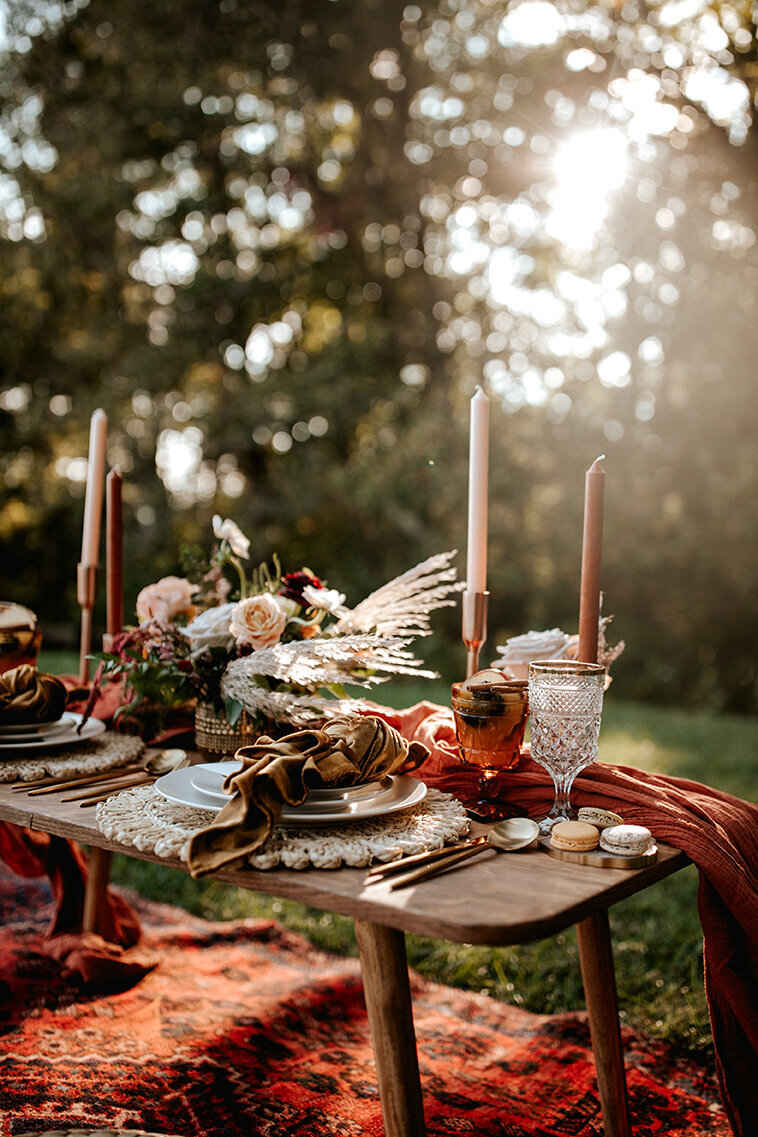 elegant table setting with ivory table chargers, white plates and candlesticks outdoors under golden hour sunlight