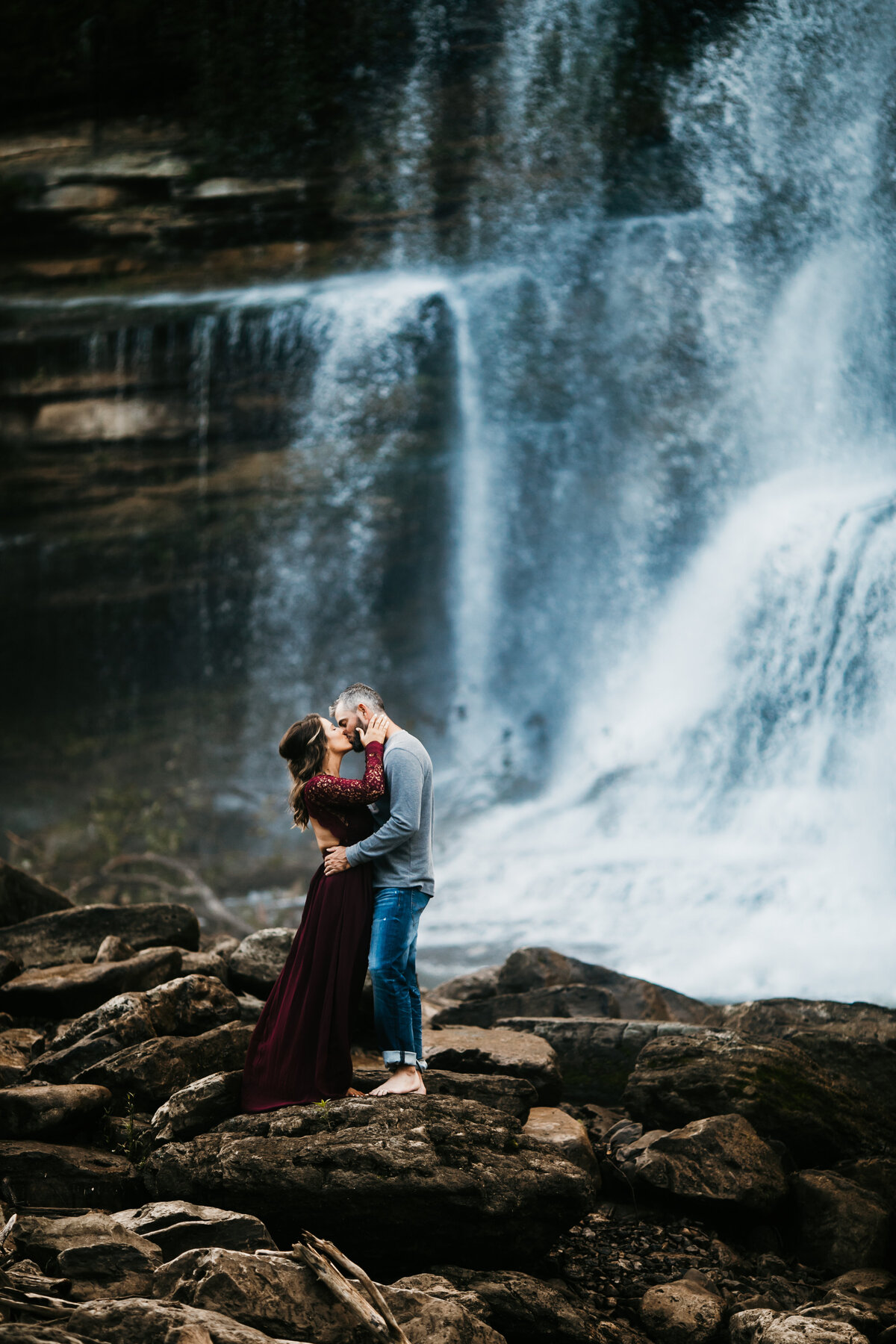 couple kissing next to a waterfall