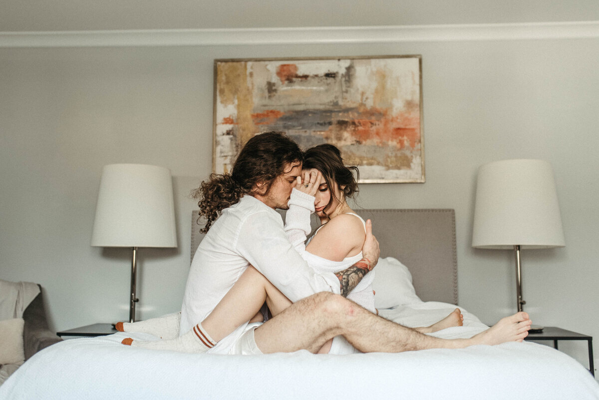 A couple embrace on a bed