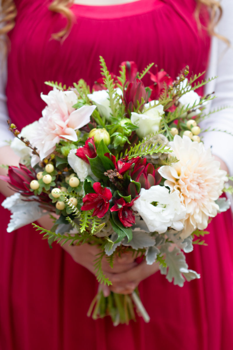 Bridesmaid wearing red dress holding a white and red bouquet of flowers