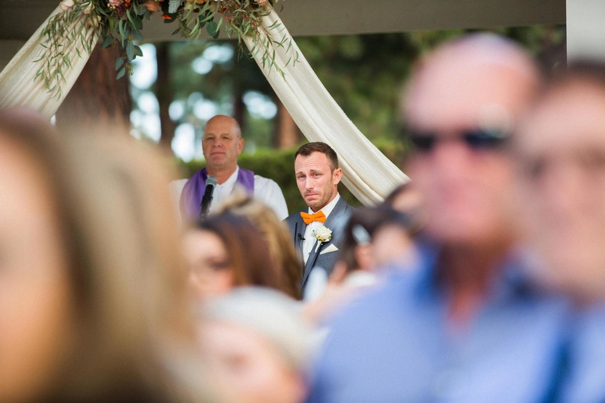 Groom watches his Bride walk up the aisle while shedding a tear