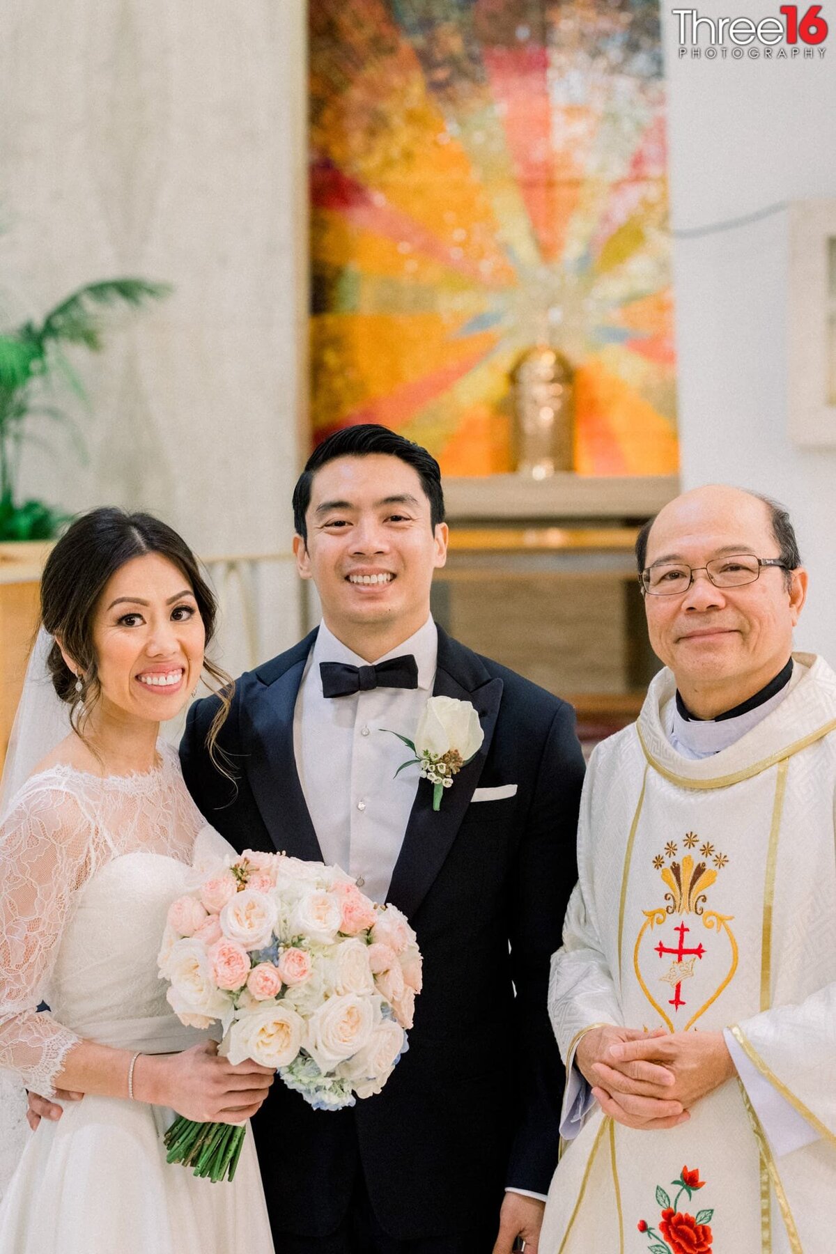 Bride and Groom pose for a photo with the priest