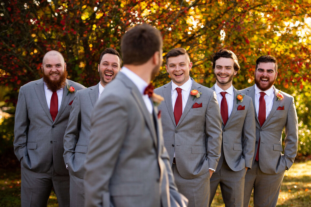 Ottawa wedding photography showing a candid moment between a groom and his groomsmen where they are all laughing taken outside at Strathmere wedding venue.