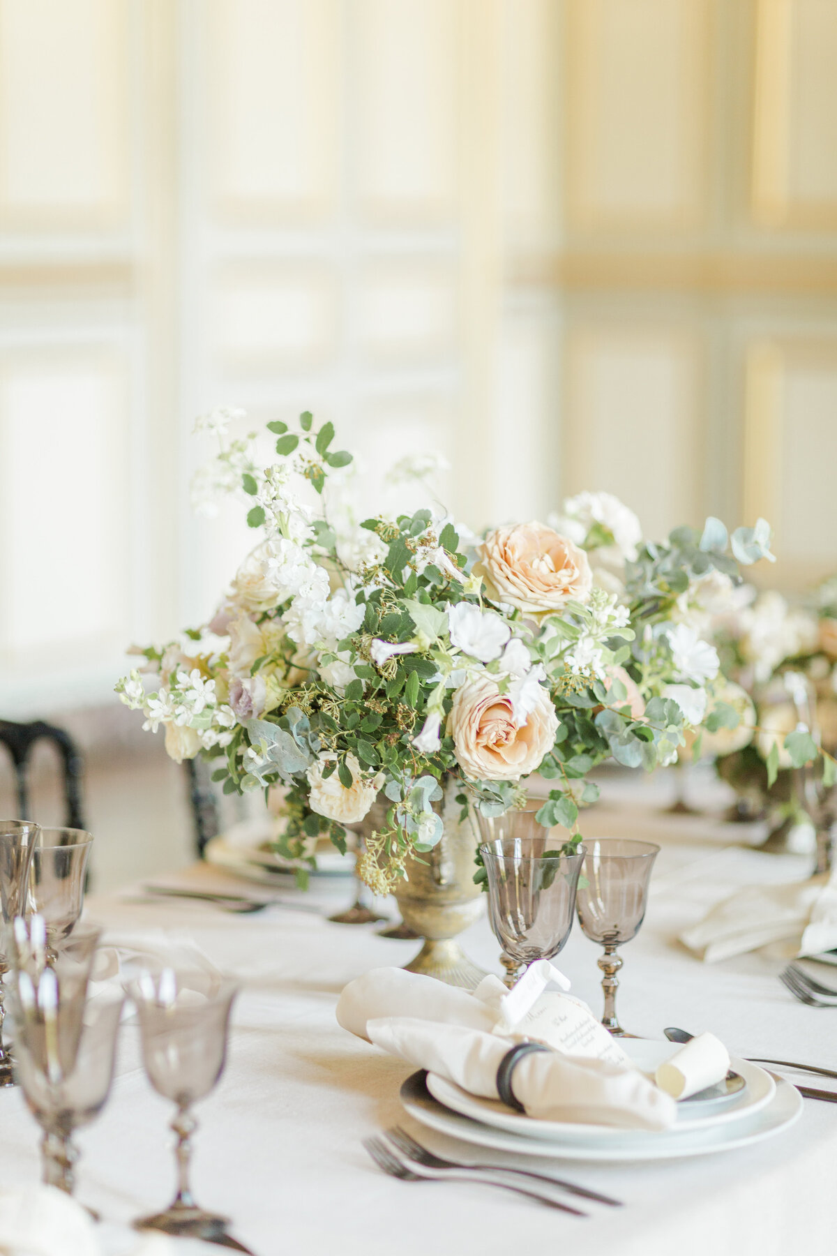 A detail image of a stunning reception tablescape featuring a large bouquet of roses and greenery. Captured by Lia Rose Weddings
