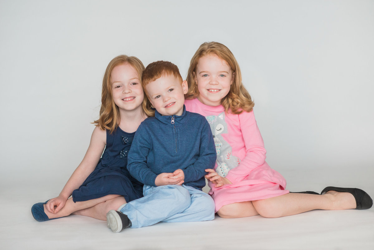 red head brother and two sisters posing for holiday portrait