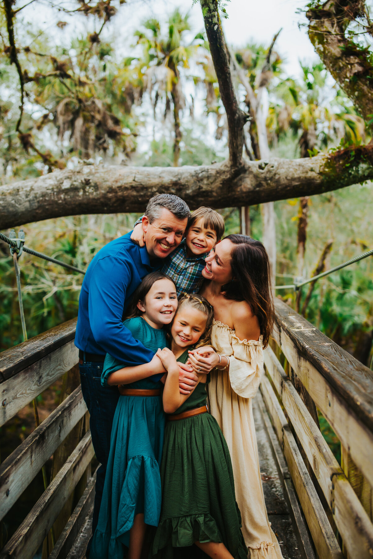 a family of 5 hugging on a suspension bridge a state park in fl