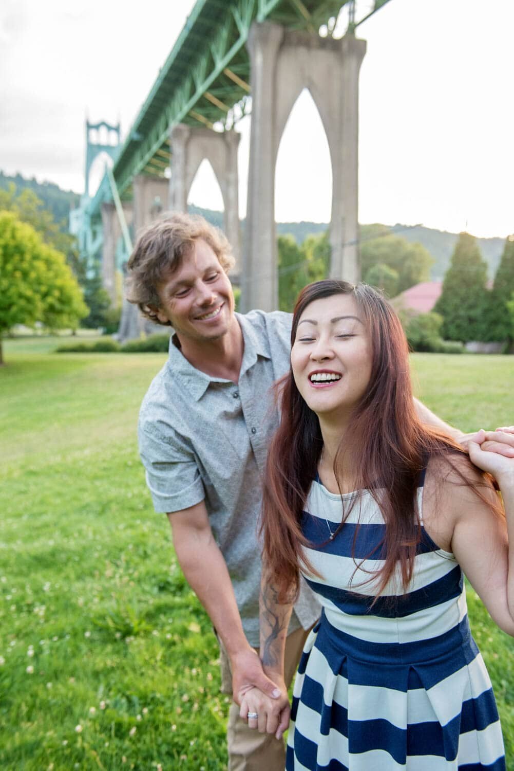 a man tries to hold back a woman under the st johns bridge at cathedral park