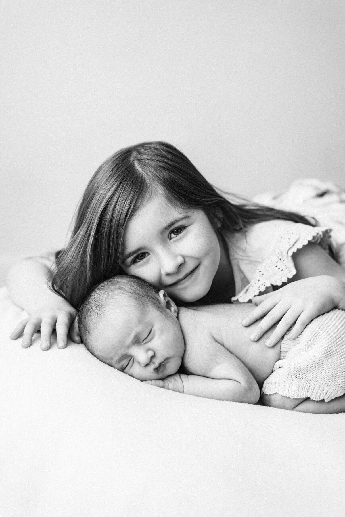 a girl cuddling her baby brother who is sleeping at billingshurst newborn photoshoot