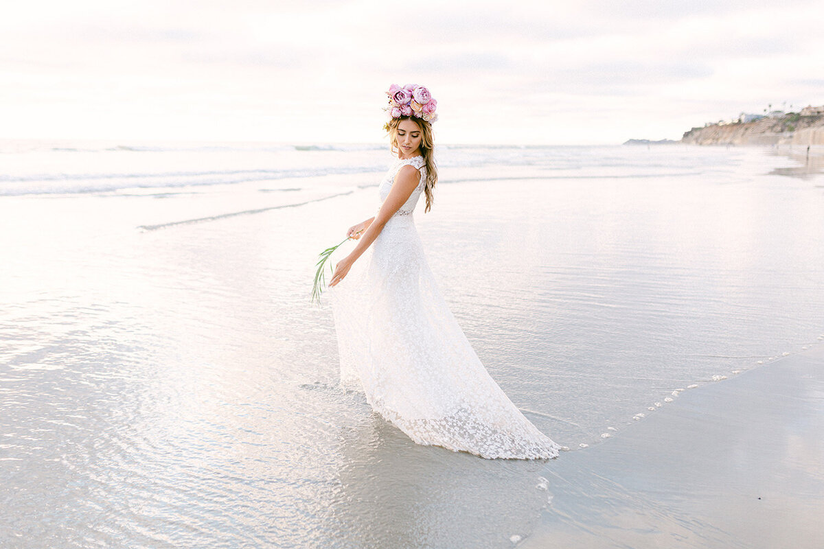 bride in wedding dress walking into the ocean