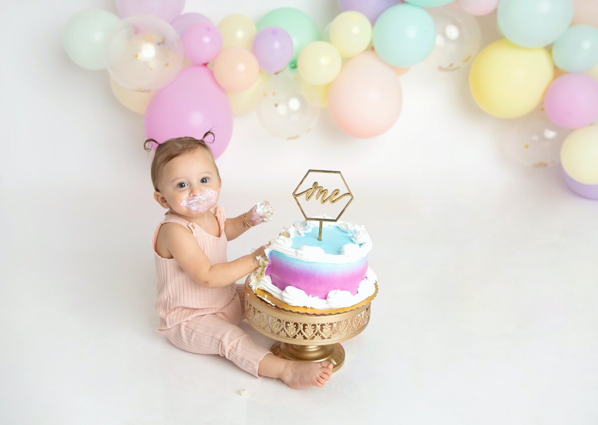 Toddler girl cake smash with pastel balloons