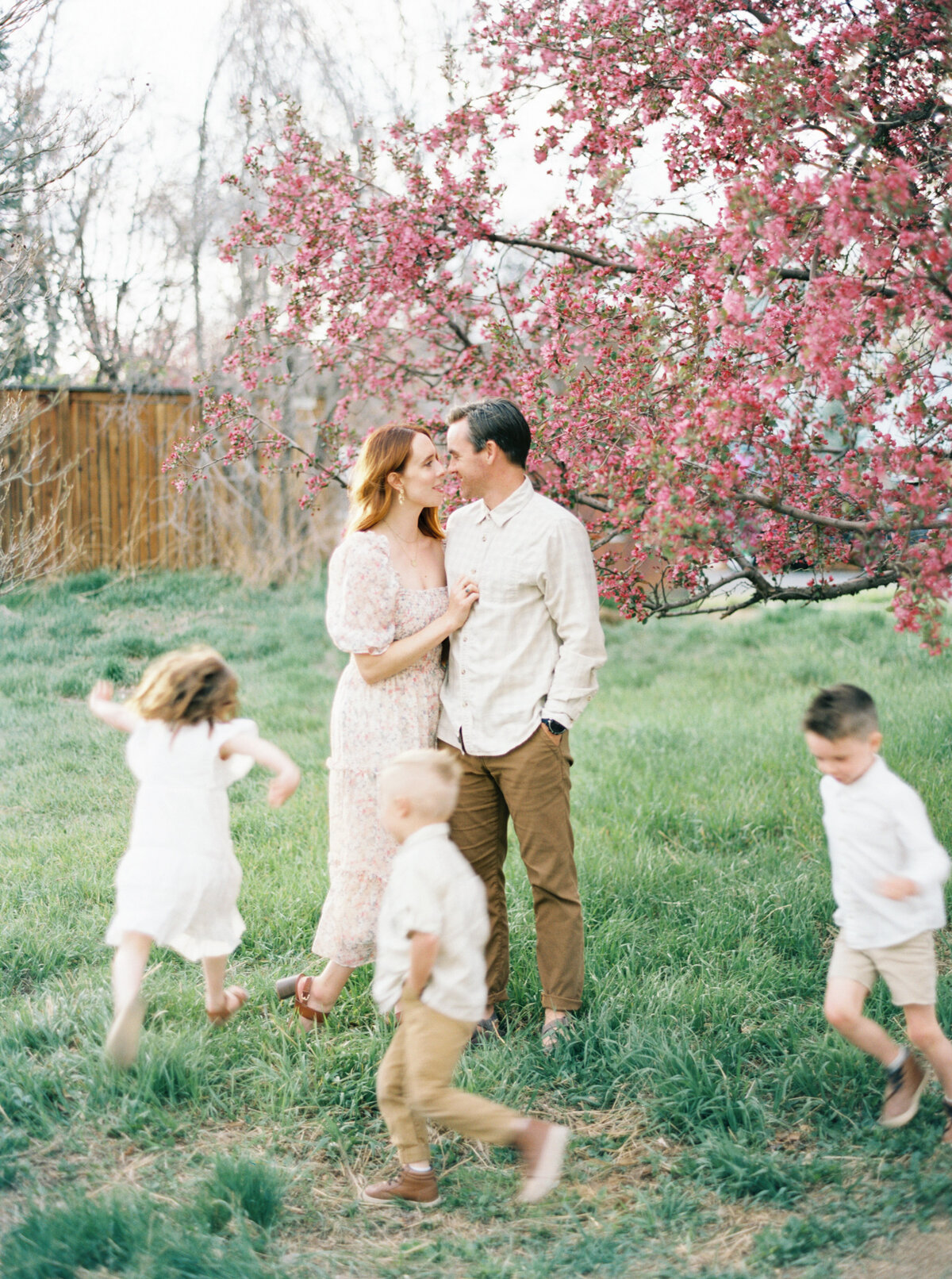 Family in field under blossoming trees.