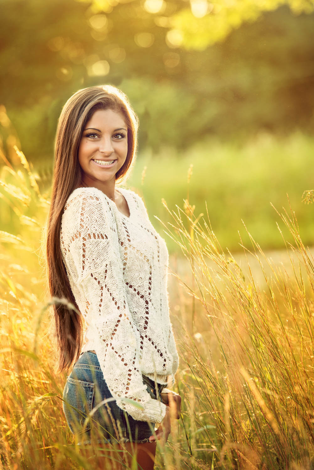 high school senior photo of girl in white sweater and cutoff jeans in the sunlight