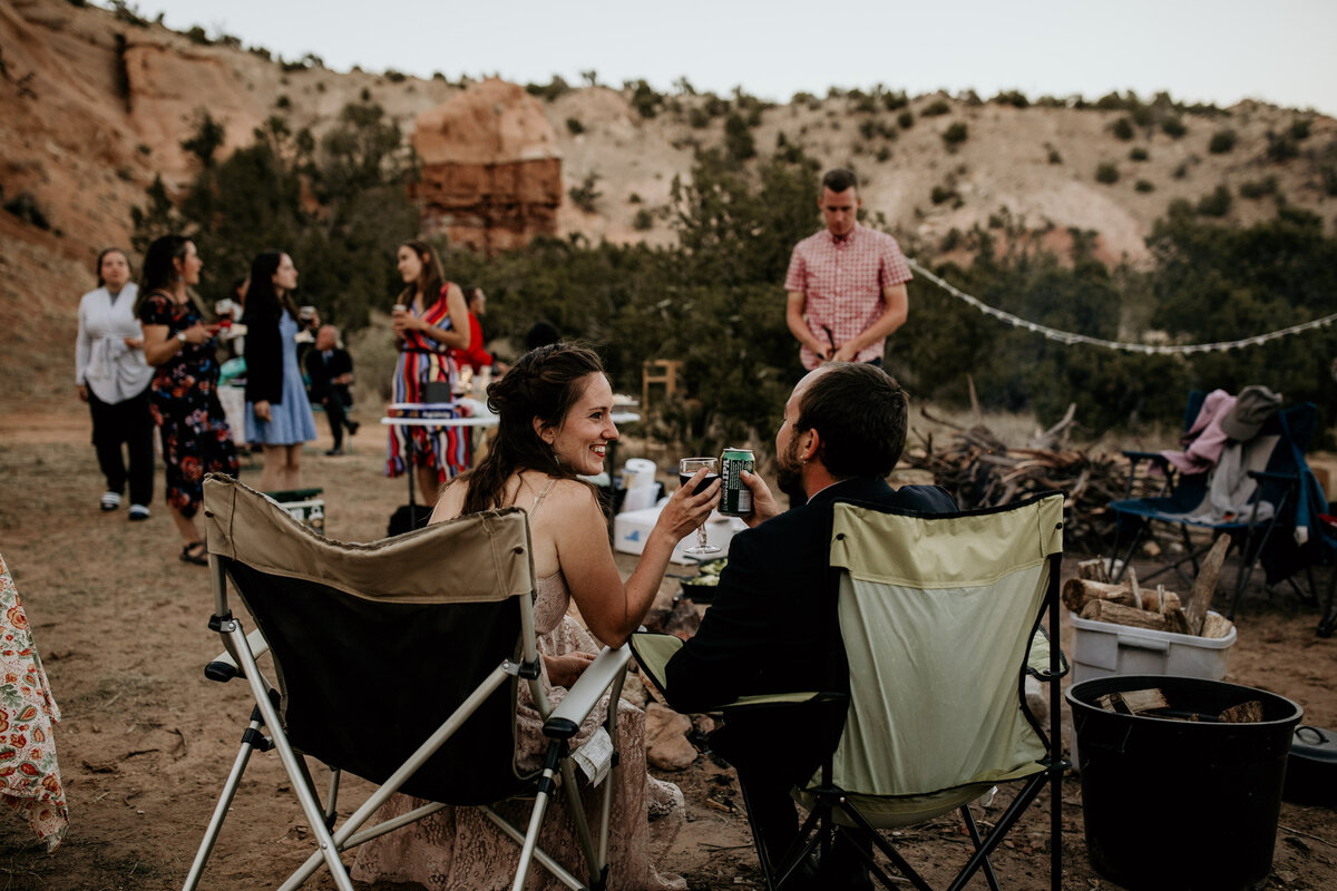eloping couple toasting and laughing by campfire