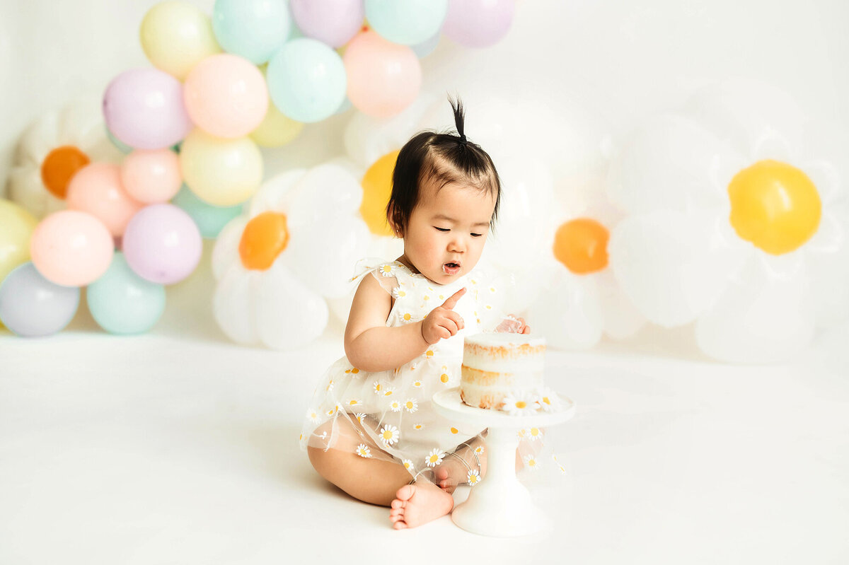 Baby girl digs into her birthday cake during Cake Smash Photoshoot in Asheville, NC.