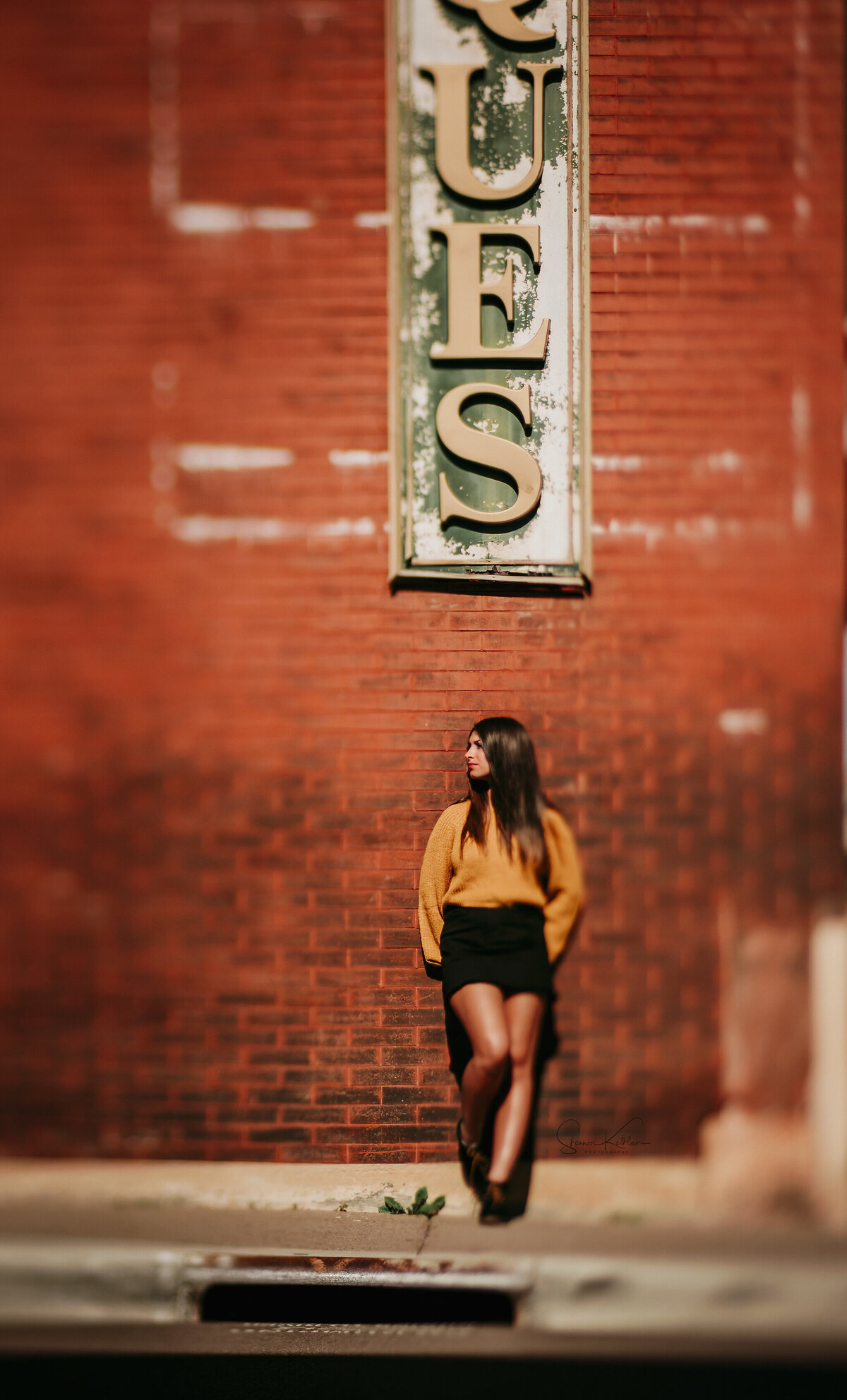 female standing against a red brick wall in stillwater