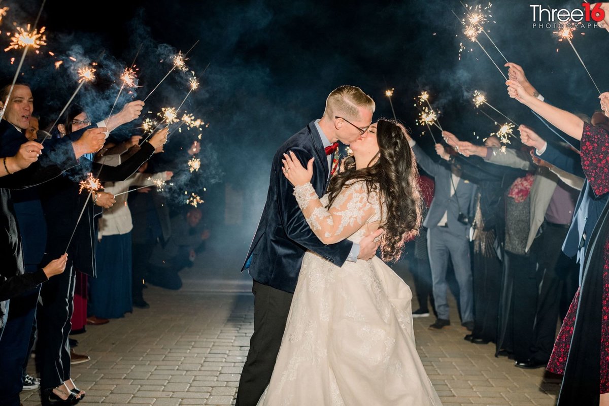 Bride and Groom share a kiss along the sparkled lit aisle