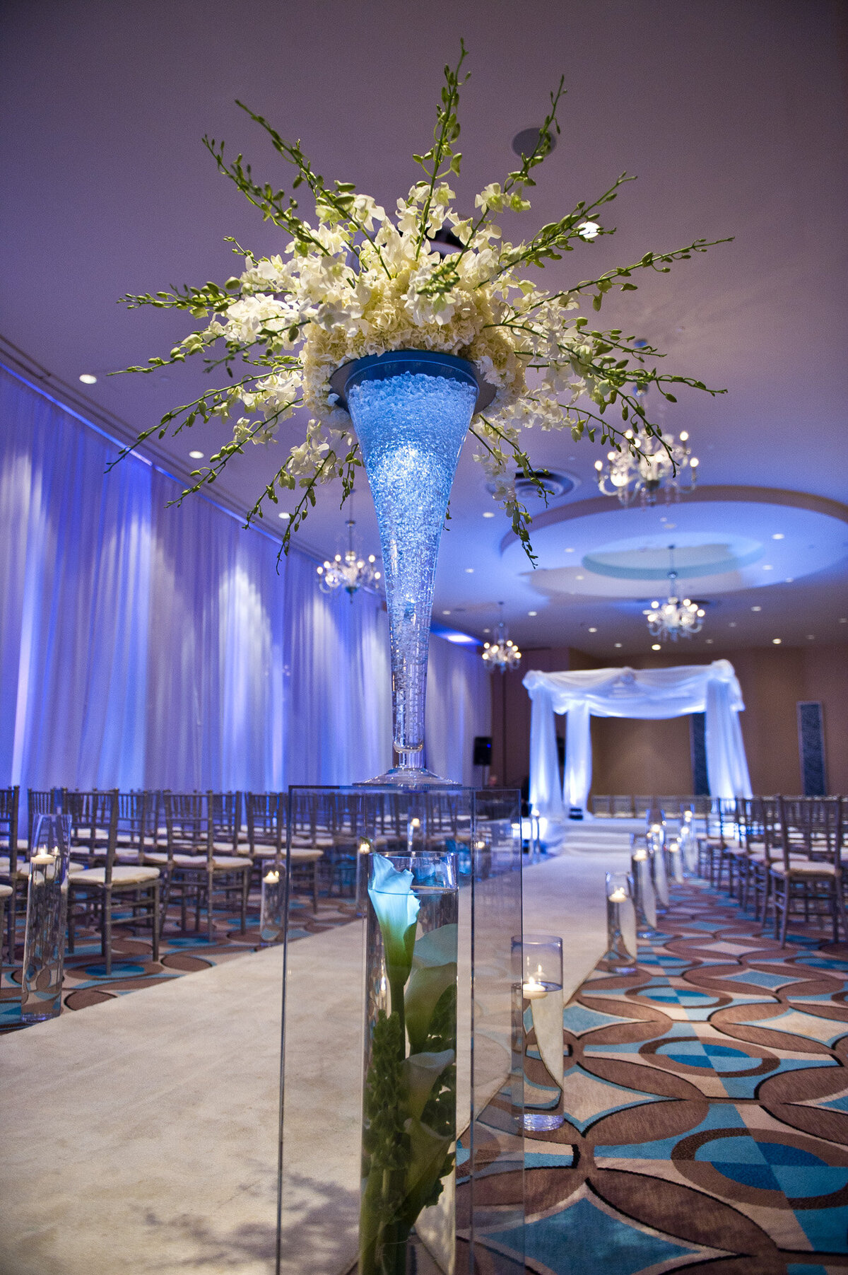 Indoor wedding ceremony site with white draping and florals