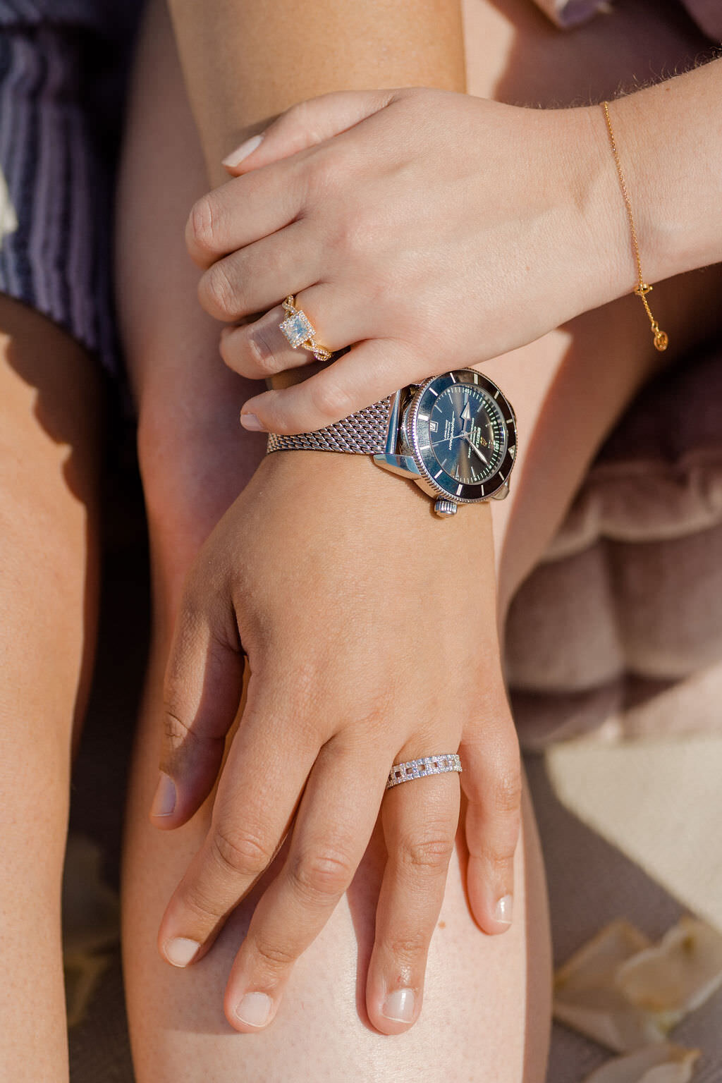 woman's hand on another's knee with both of their hands on top of each other showing off engagement rings