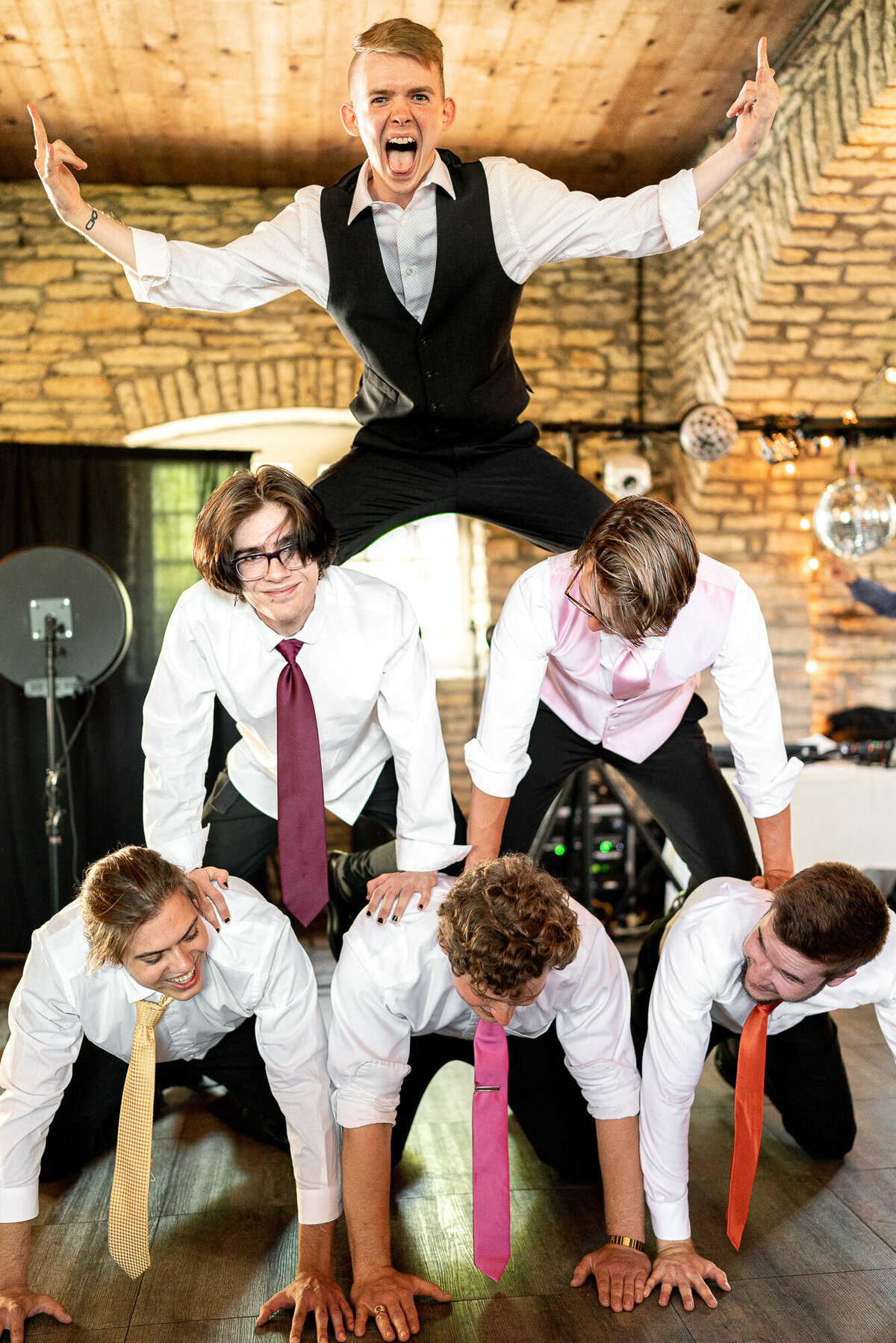 Groom stands on a pyramid of his groomsmen.
