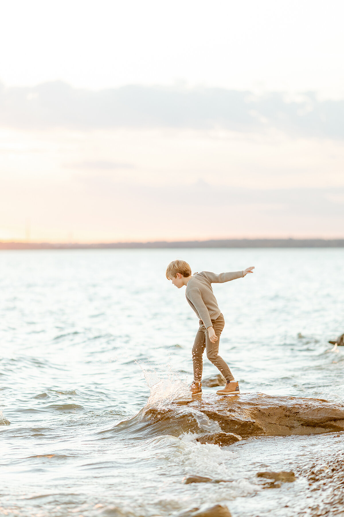A young boy playing in the water of a local DFW lake for his family photos.