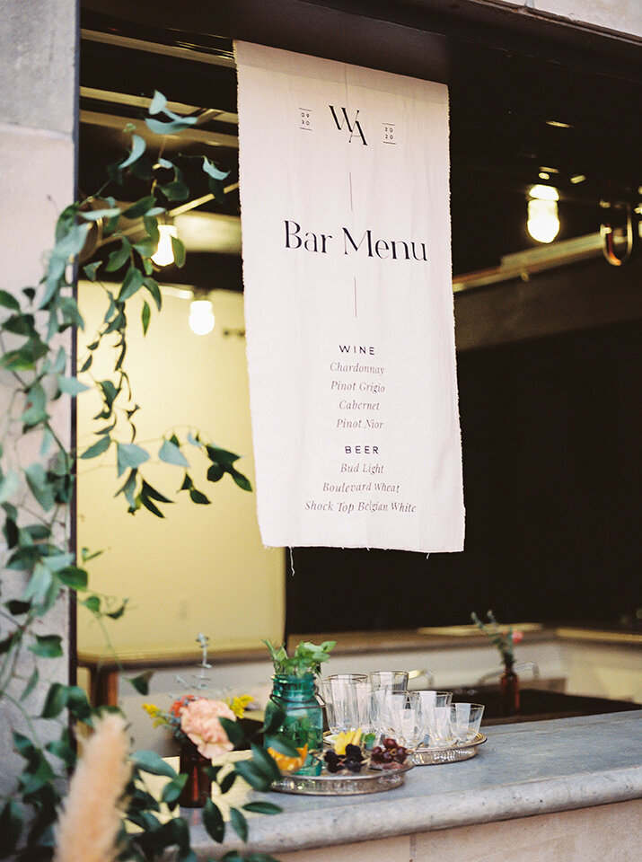 A white drink menu with black font hangs off the ceiling in the bar area outside.