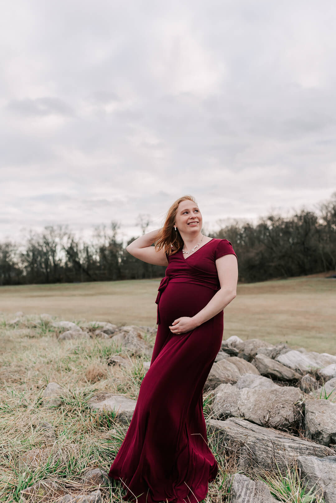 A pregnant woman with red hair striking a pose at Centennial Park by Denise Van Photography