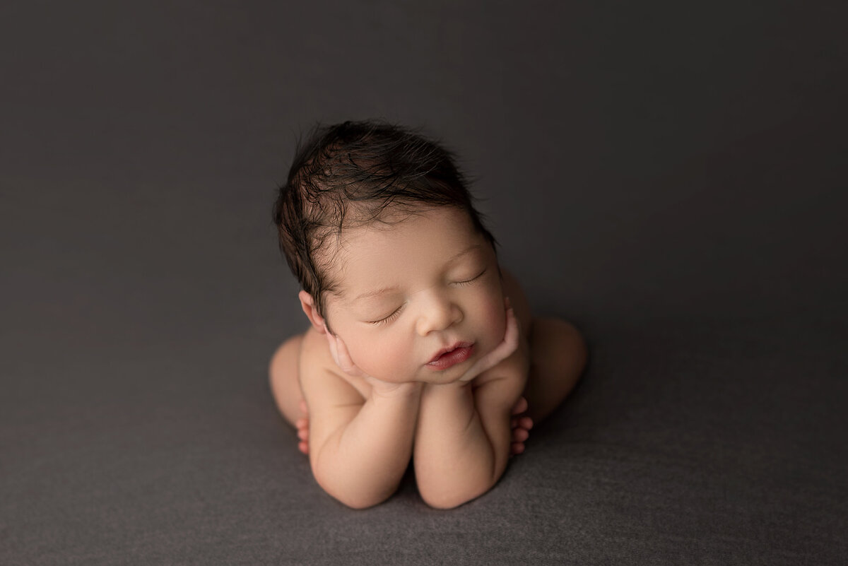 Philadelphia's best newborn photographer, Katie Marshall, captures a bare baby sleeping in froggy pose with his hands underneath his chin.