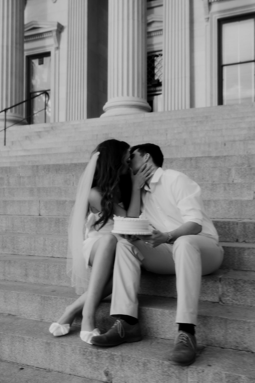 Couple kissing while sitting on stairs of US Custom House in Charleston for engagement photo session