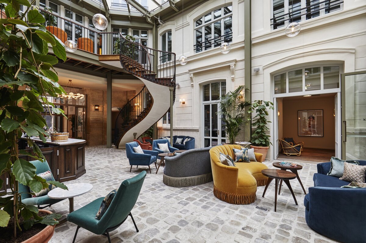 Parisian courtyard with cobblestone floor, vintage furniture and spiral staircase