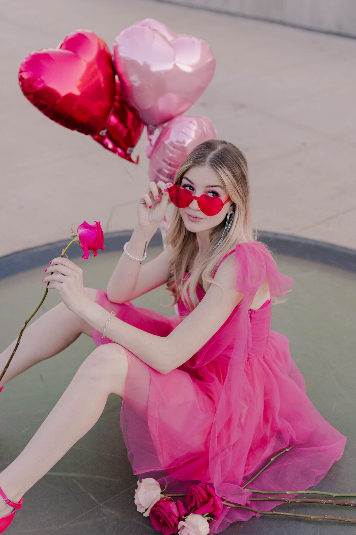 barbie model poses sitting down with heart-shaped balloons and sunglasses on post houston rooftop