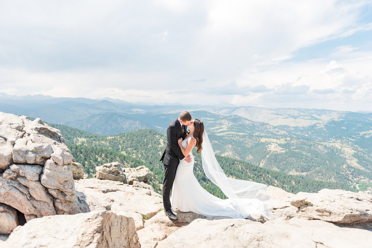 Bride and groom kissing on top of a rocky overlook in the Rocky Mountains in Colorado during their elopement.