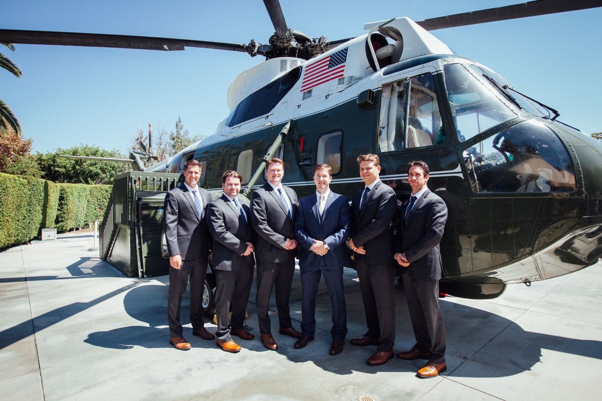 Groomsmen pose in front of the helicopter on the grounds of the Richard Nixon Library
