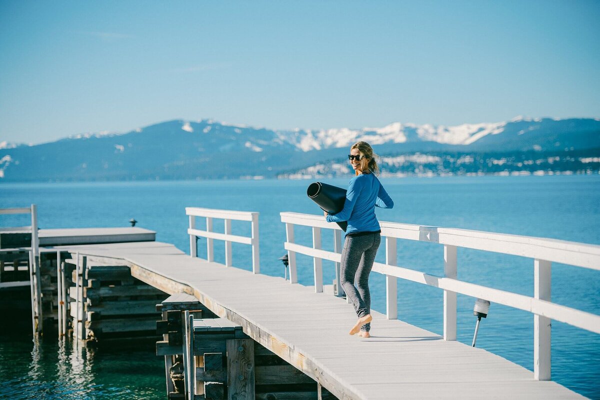 yoga teacher session on pier in Lake Tahoe walking with her mat