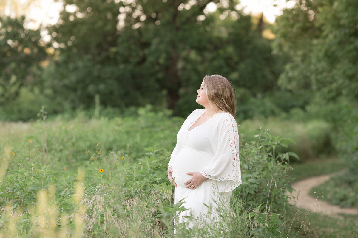 Expectant mother looks at sunset during outdoor maternity photoshoot in Louisville KY with Julie Brock Photography