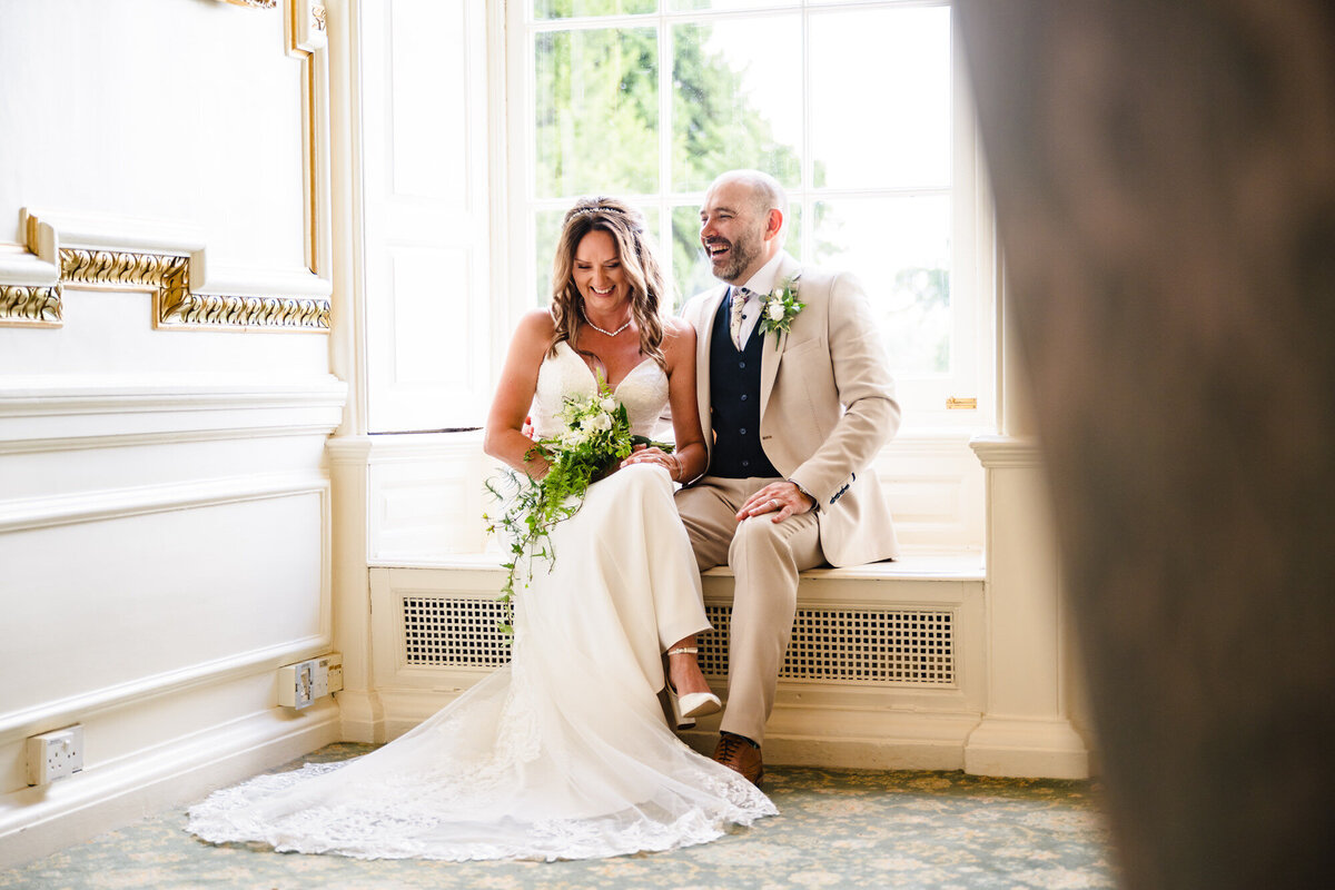 Bride and groom sat in window at Stapleford park hotel