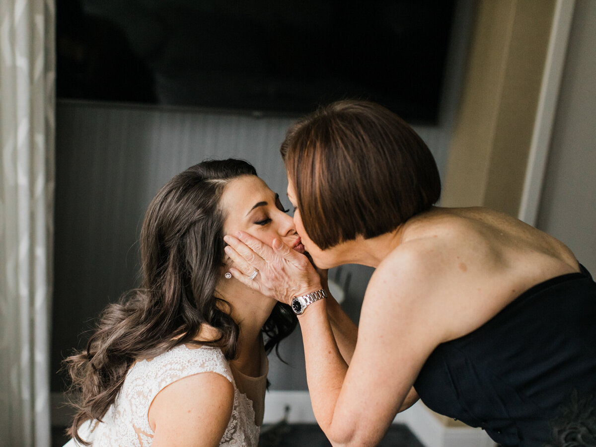 A mother of the bride kisses her daughter as they get ready for the wedding