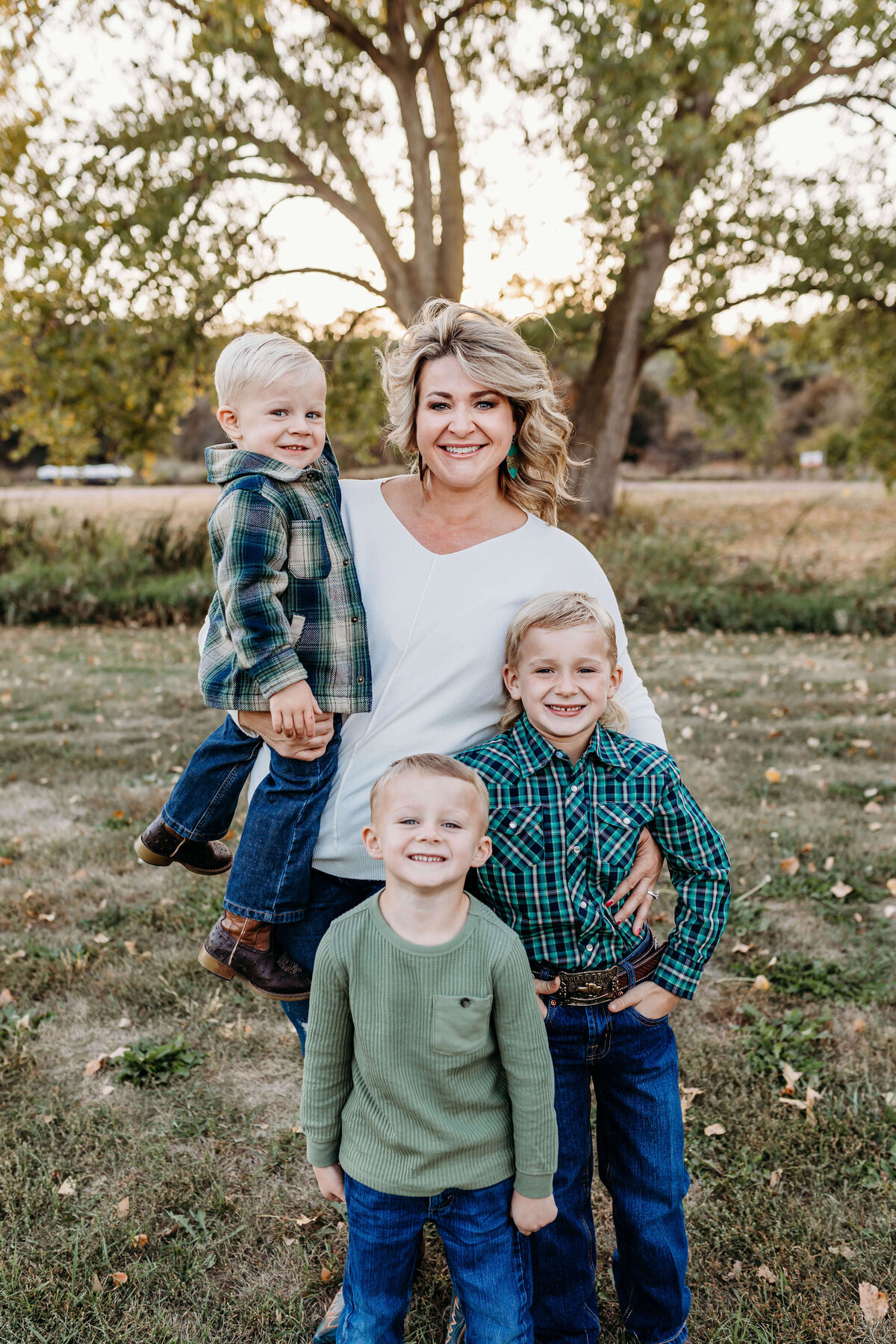 Mom is standing in an open area with her 3 boys.