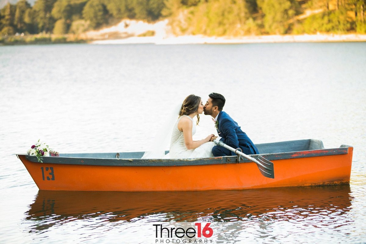 A sweet kiss between newly married couple while rowing a row boat