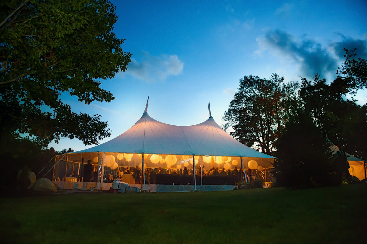 A wedding reception tent against a dusk sky.