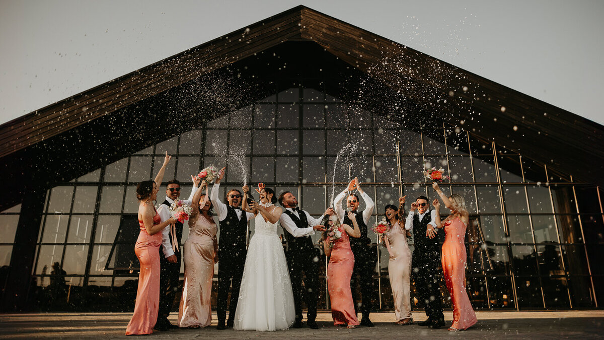 Wedding party spray champagne at The Barn at Botley Hill in South London.