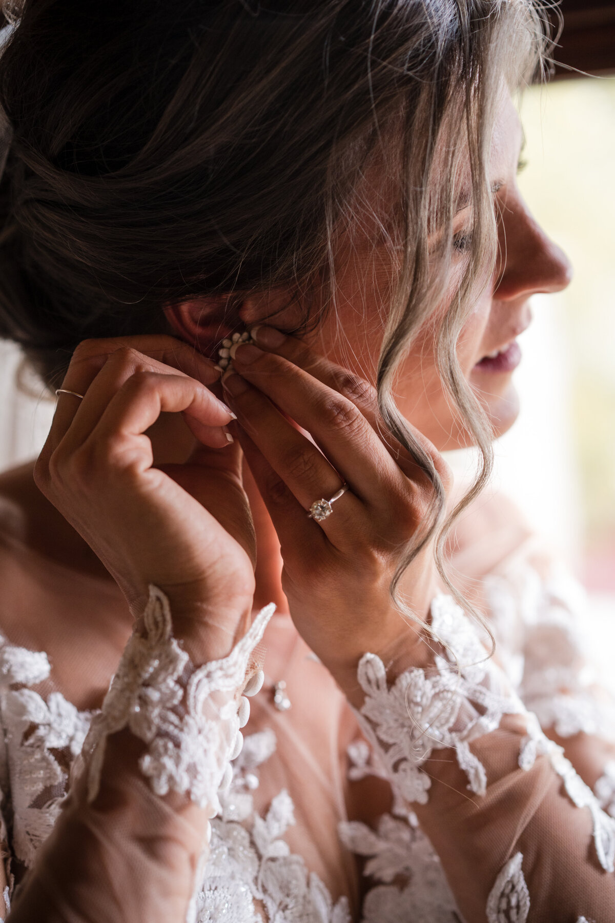 Woman putting in her earrings on her wedding day.