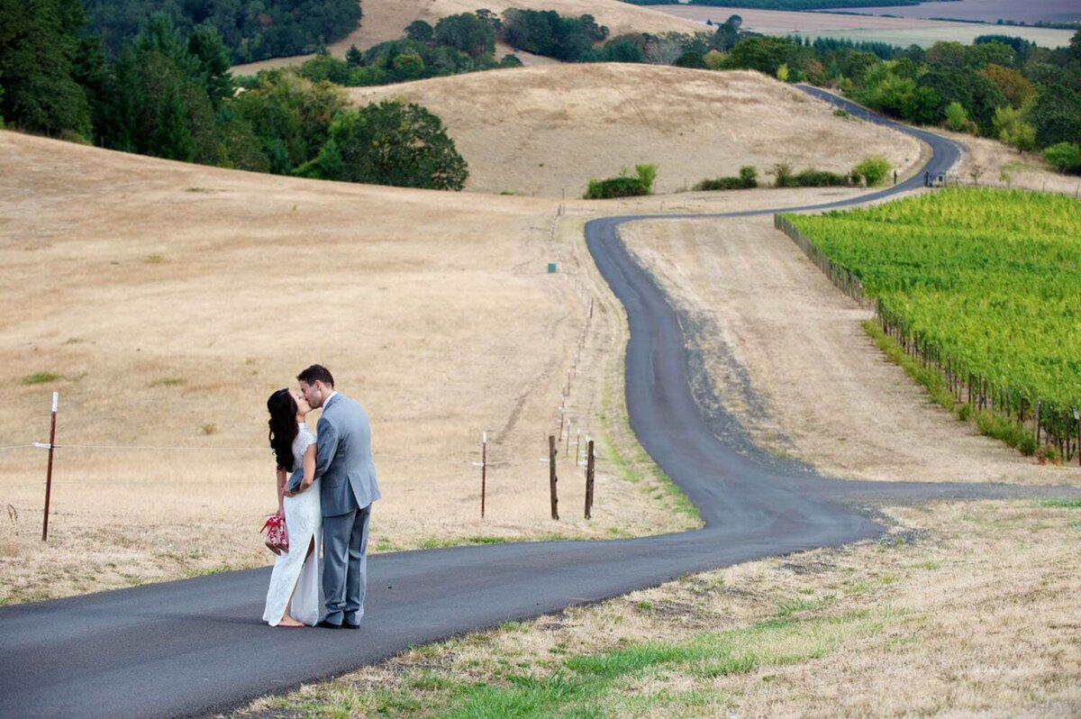a couple kiss on a long road through vineyards