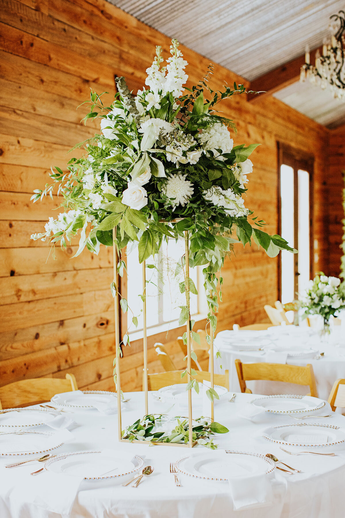 tall table top wedding centerpiece with white flowers and greenery